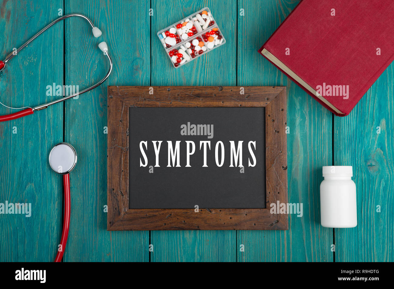 Tiermedizin Konzept - Tafel mit dem Text Symptome", Buch, Pillen und Stethoskop auf Blau Holz- Hintergrund Stockfoto