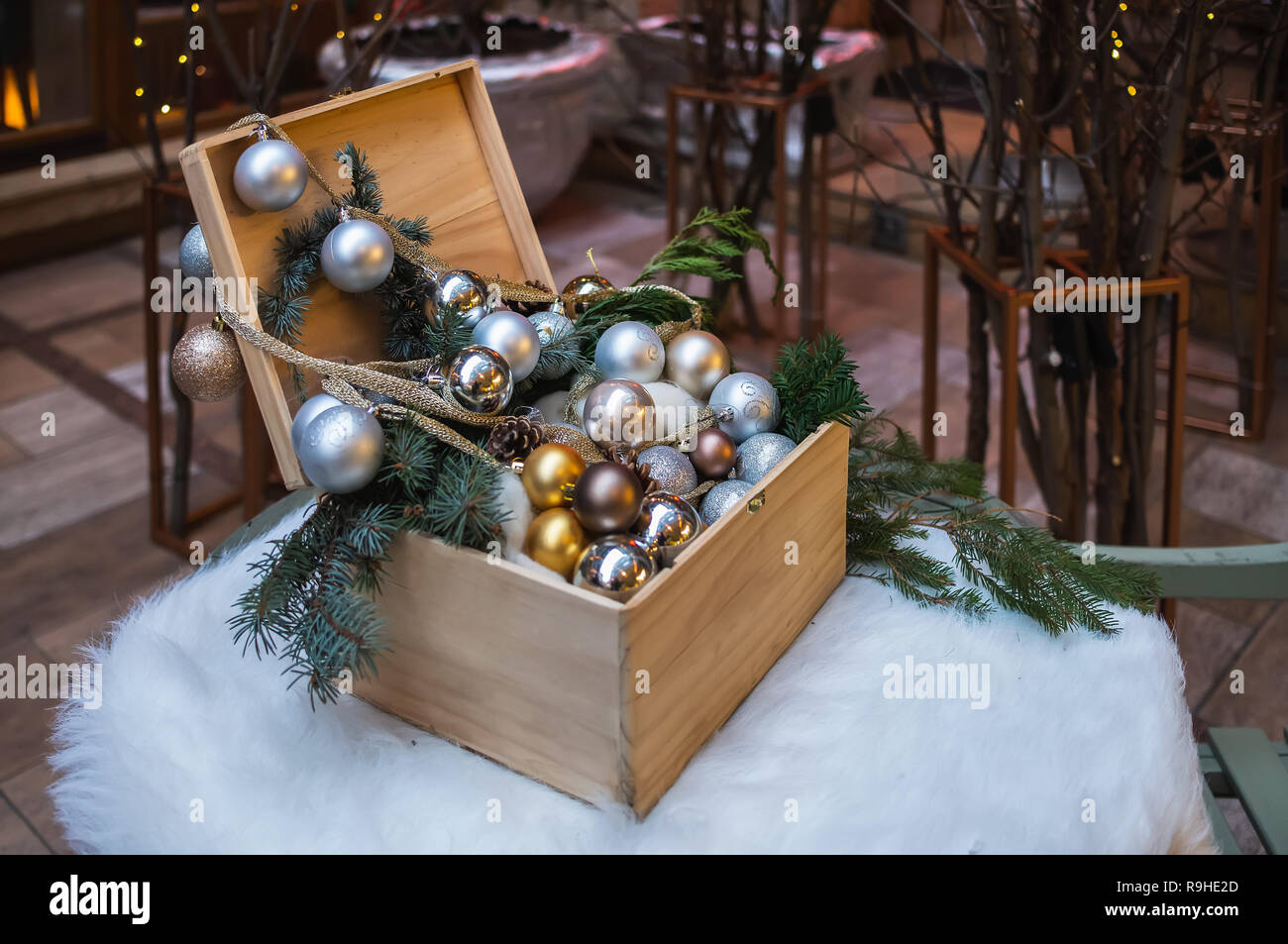 Ein offener Kasten mit Weihnachten Spielzeug ist auf dem runden Tisch. Die Tabelle ist mit weißer Haut gelegt. Stockfoto
