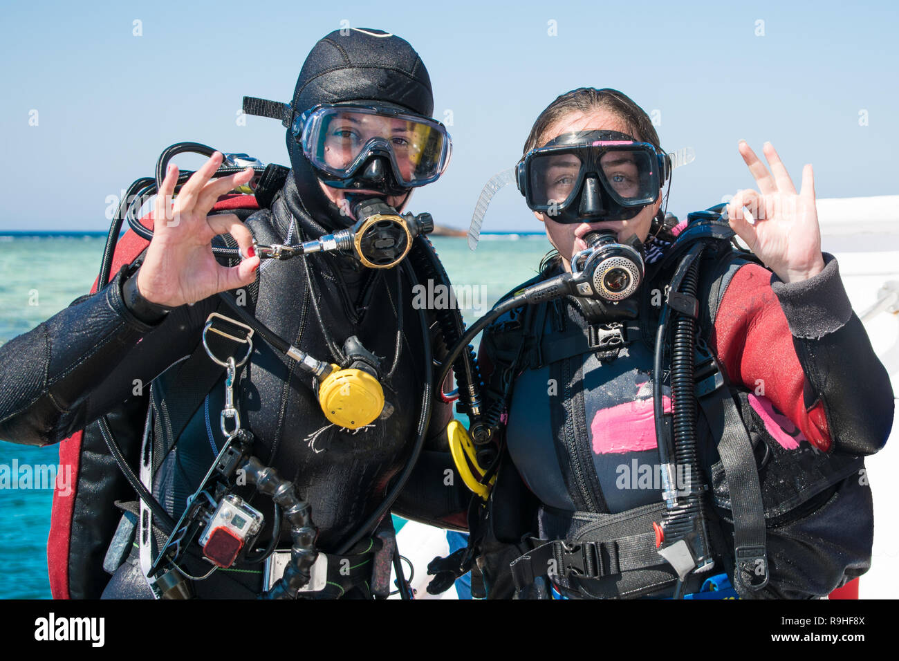 Zwei glückliche Taucher im Neoprenanzug und Masken mit Octopus in mouthes  auf dem Hintergrund der azurblauen Meer OK angezeigt. Happy Girls in  Neoprenanzüge. tauchen. Tauchen Stockfotografie - Alamy