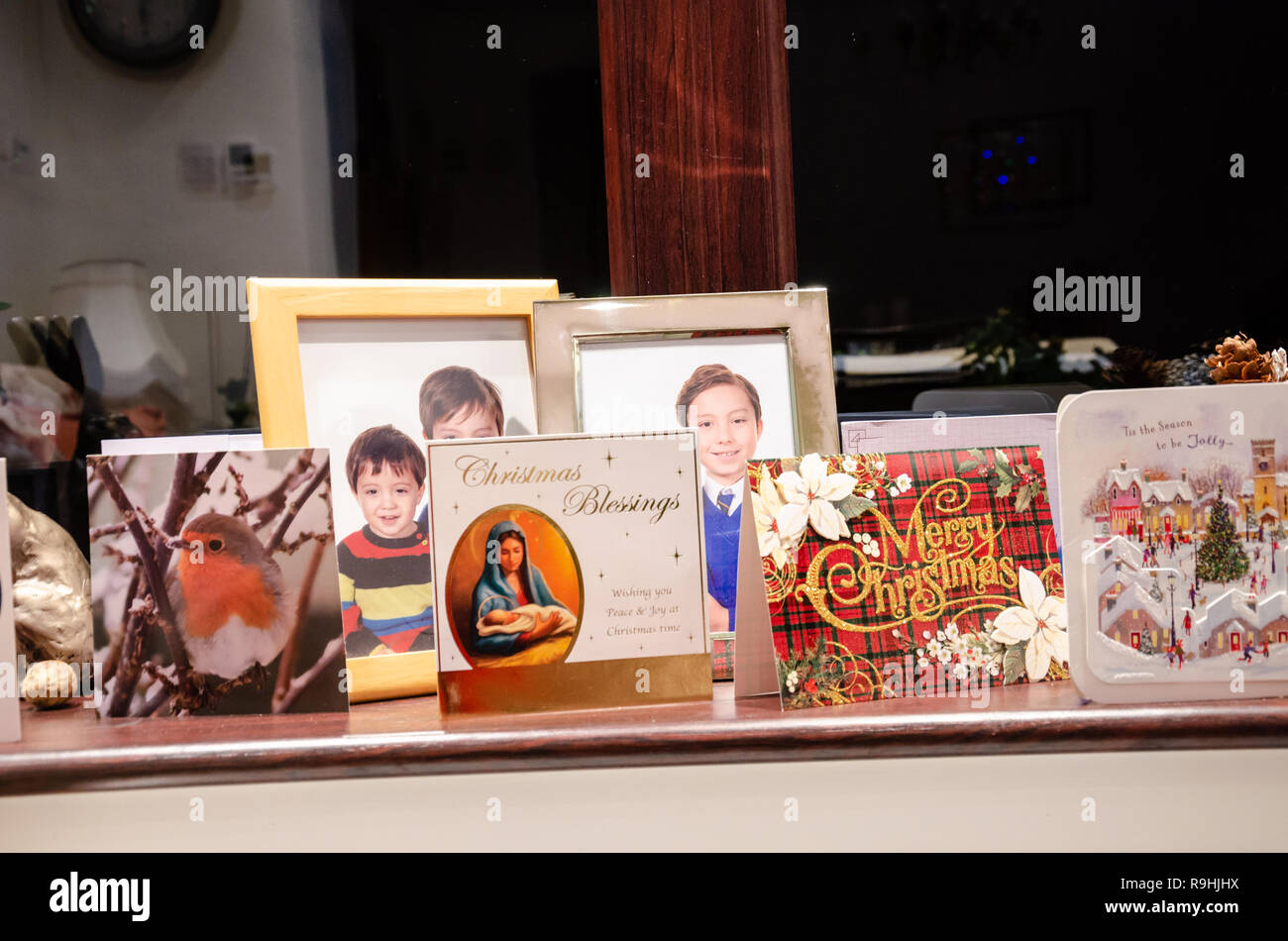 Saisonale Weihnachtskarten auf dem Fensterbrett neben Familienfotos. Stockfoto
