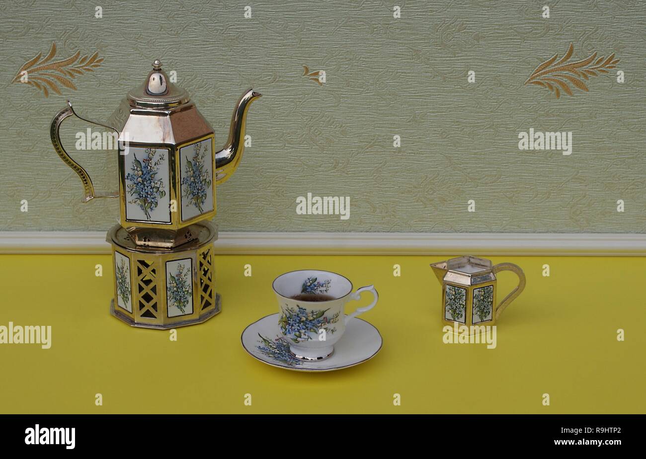 Englisch Teetasse, Untertasse, versilbert Teekanne auf einem silbernen Herd, und Sahne Kanne, mit floralem Dekor Stockfoto
