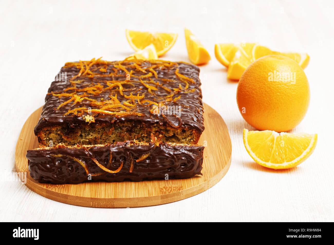 Schokolade und Orange mit einem Stück Kuchen Abschneiden in der Nähe von Orange auf weißem Holz- Hintergrund. Flache konzentrieren. Stockfoto