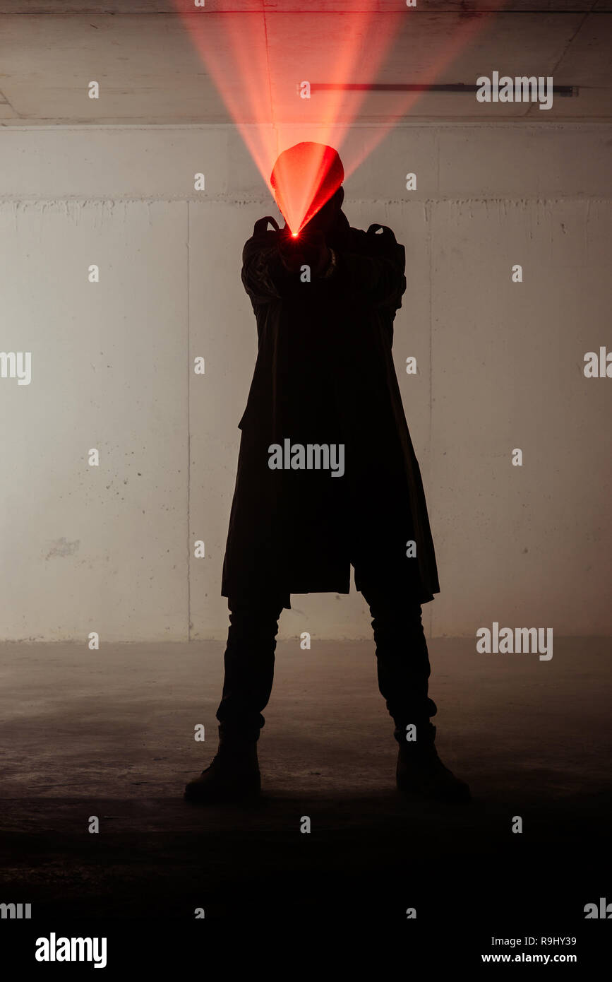 Ein Mann steht in einem dunklen Raum mit einem Laser Gewehr in den Händen Stockfoto