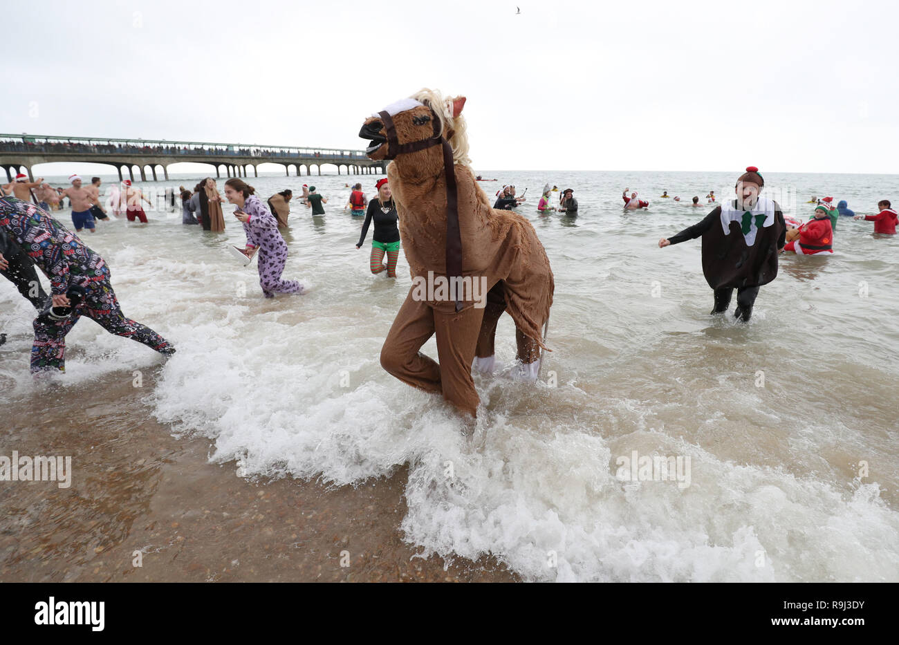 Menschen in Fancy Dress an den jährlichen White Christmas Dip in Boscombe Pier, Bournemouth zu nehmen Geld für Macmillan Pflege lokal zu erhöhen. Stockfoto