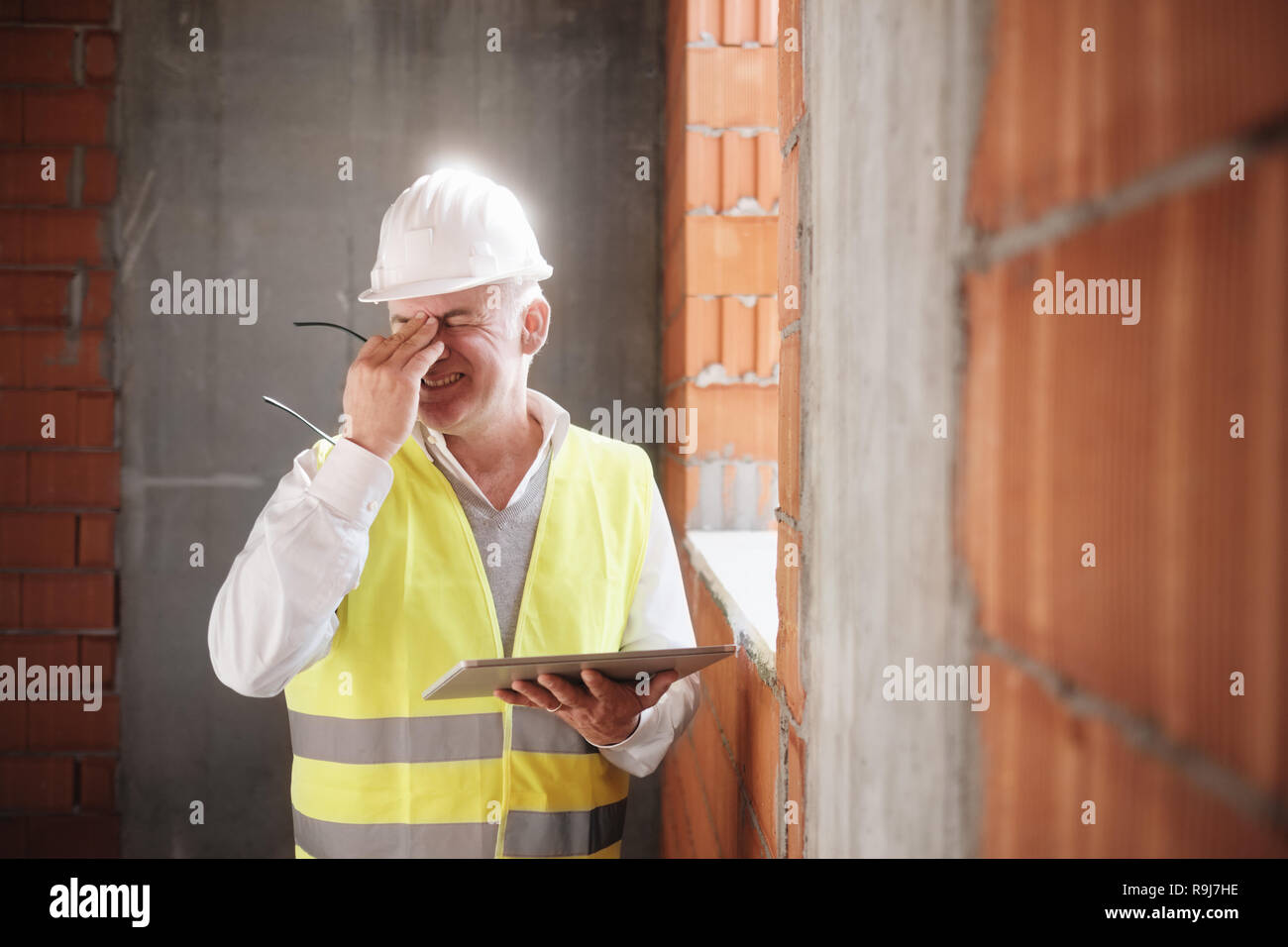 Menschen, die in Baustelle. Kranken Mann bei der Arbeit im neuen Haus im Haus. Architekt mit Kopfschmerzen mit digitalen Tablet Stockfoto