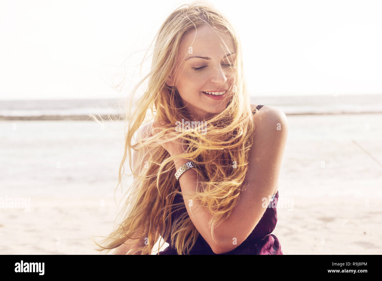 Glückliche junge Frau an einem windigen Tag am Strand Stockfoto