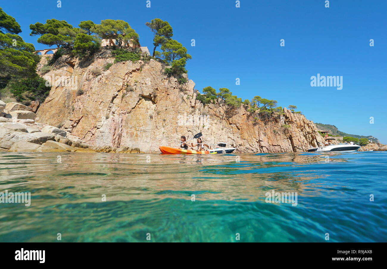 Junge Frauen Paddel Kayak auf dem Mittelmeer vor einer felsigen Küste, Aiguablava, Begur, Katalonien, Costa Brava, Spanien Stockfoto