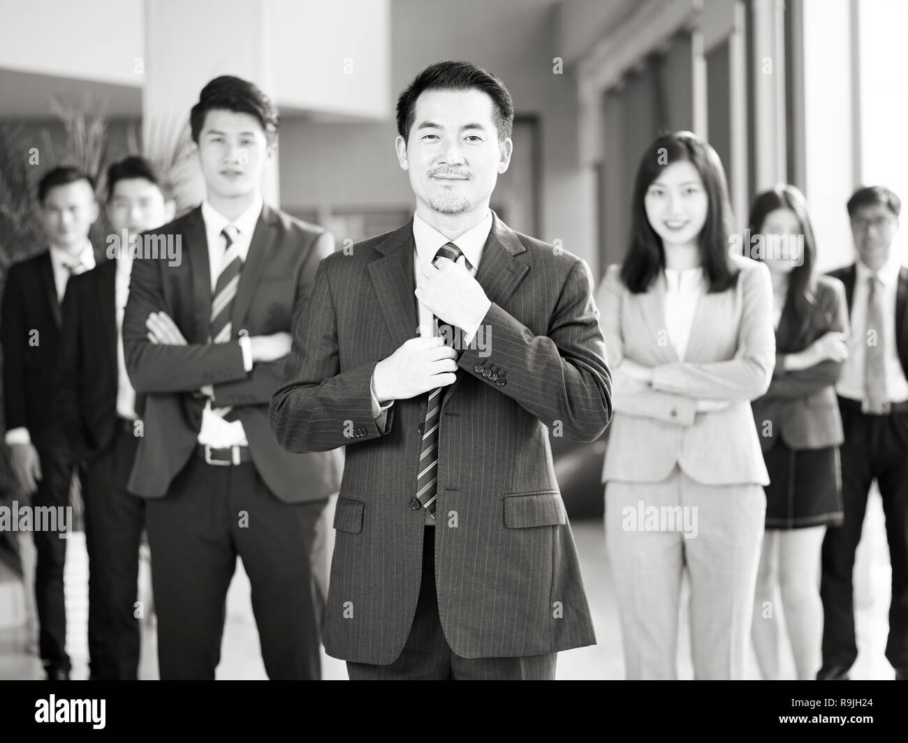 Porträt einer Mannschaft der Erfolgreichen asiatischen Unternehmer und Unternehmerinnen, in die Kamera lächeln suchen, Schwarz und Weiß. Stockfoto