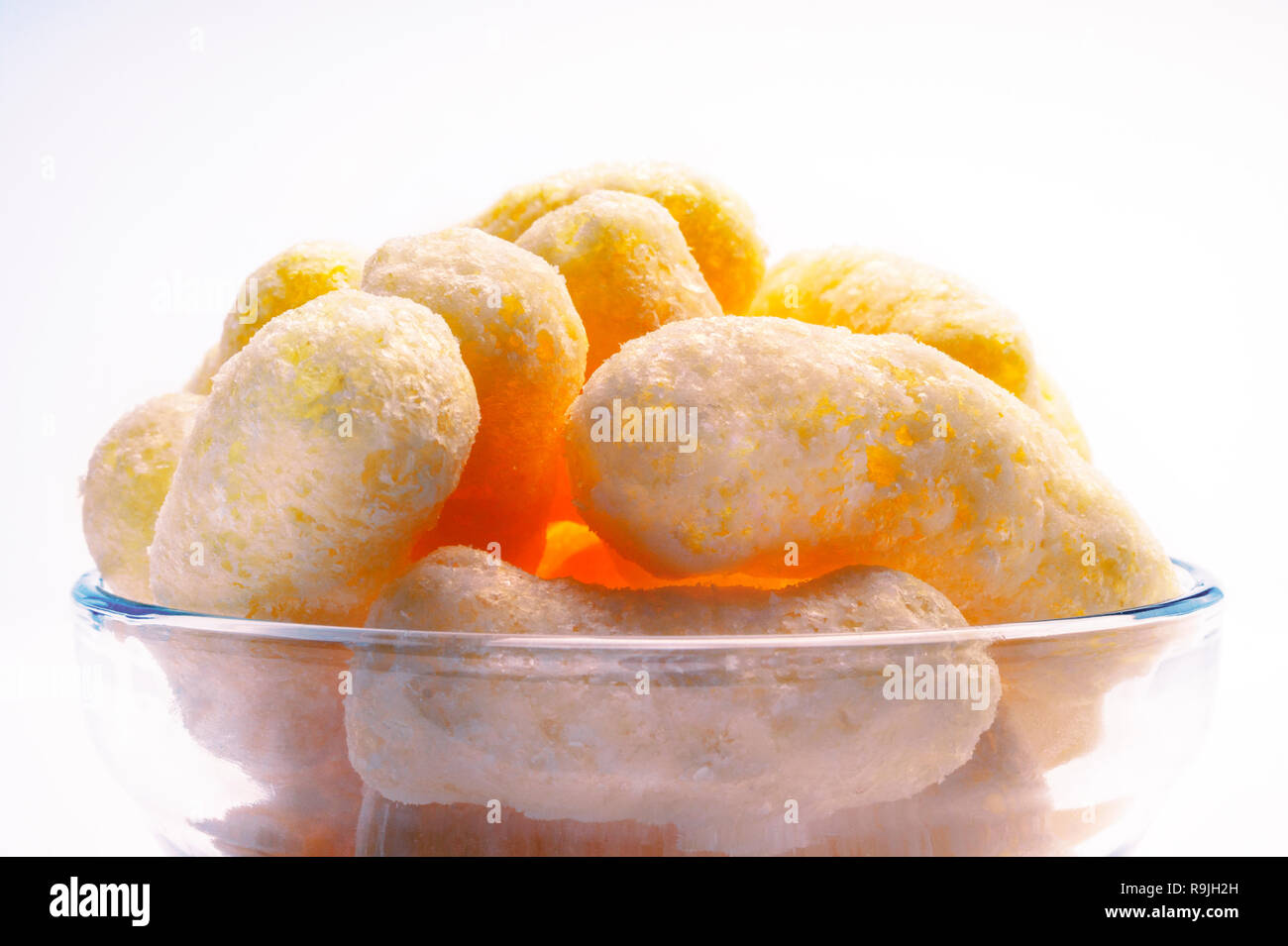 Gelber Mais Puffs in einer Glasschale. Crunchy aromatisiert aufgeblasen Snacks. Party, Film, TV, Game Snacks. Stockfoto