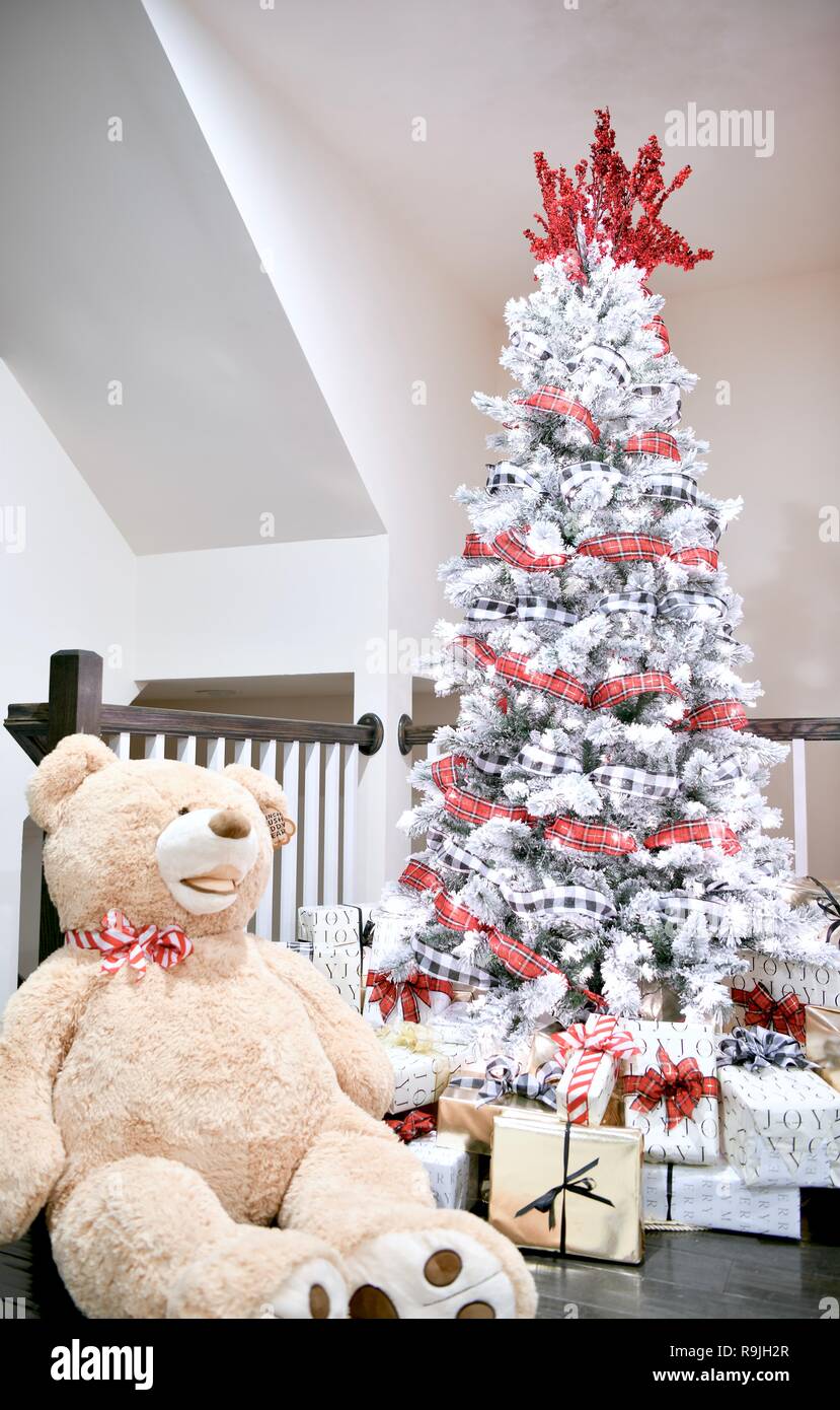 Weihnachtsbaum mit Geschenken und einem großen Ausgestopfter Teddybär. Stockfoto
