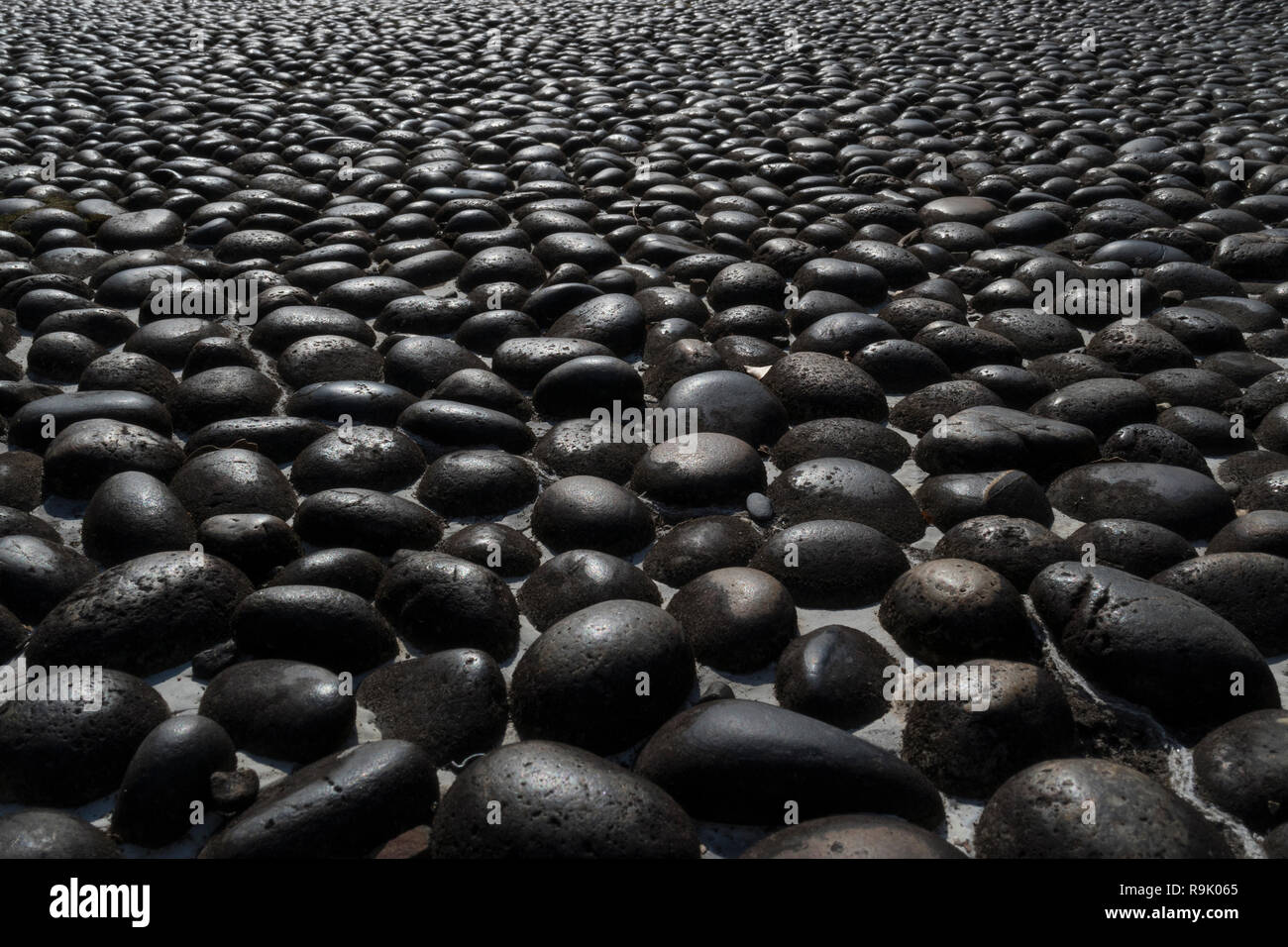 Pflaster mit runden schwarzen Felsbrocken full frame Stockfoto