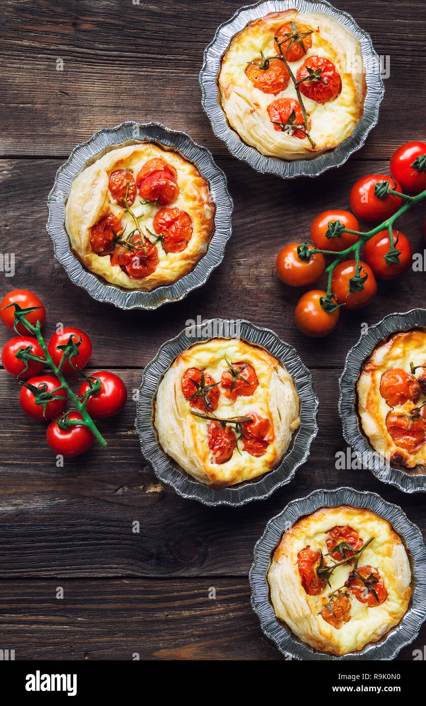 Frische hausgemachte Torten mit Cherry Tomaten und Ziegenkäse auf rustikalen Holzmöbeln Hintergrund. Ansicht von oben. Stockfoto