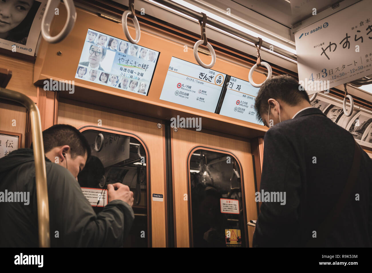 Zwei Männer wartet der Zug auf der Tokyo Metro Ginza Linie Zug in Ginza Station ankommen zu lassen. Bildschirm angezeigt, der die Station Informationen und Austausch Stockfoto