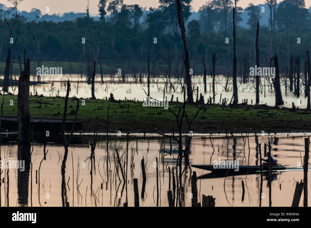 Thakhek, Laos - 19. April 2018: Boat Crossing eine atemberaubende Landschaft toter Bäume bei Sonnenuntergang in einem abgelegenen Gebiet von Laos gemacht Stockfoto