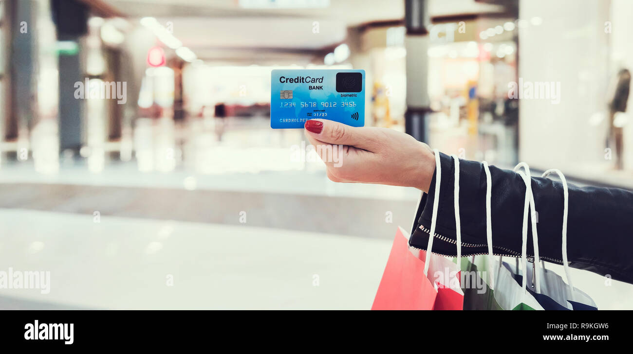 Horizontale Aufnahme des Ernteguts weibliche Hand, die Stirnseite der lesbaren Kreditkarte am Mall Hintergrund. Weibliche shopaholic Mit bank Transaktionen zu bezahlen Stockfoto