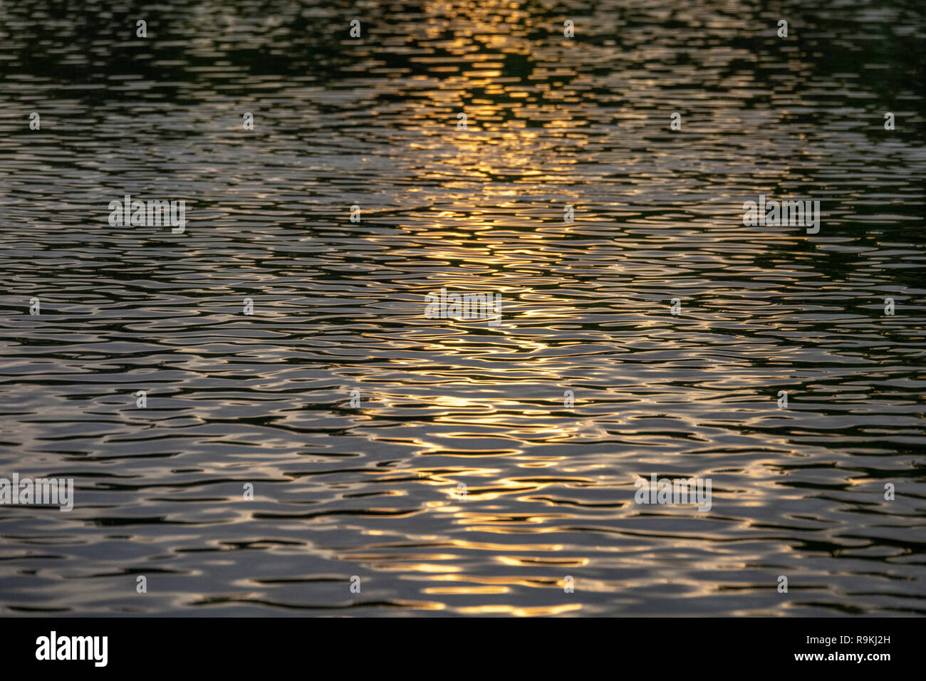 Die untergehende Sonne auf dem Fluss Wasser Muster widerspiegelt Stockfoto