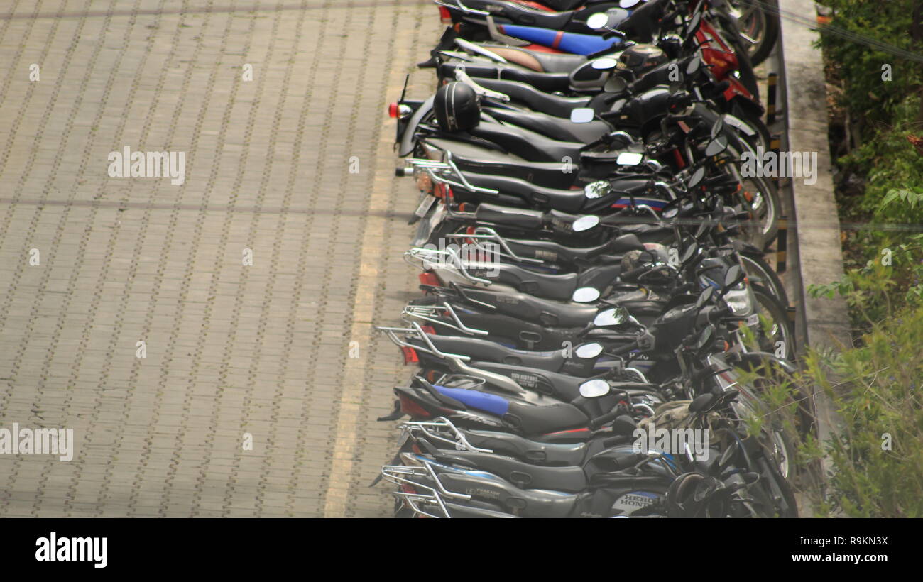 Fahrräder und Roller dick in einer Zeile in Indien geparkt. Stockfoto