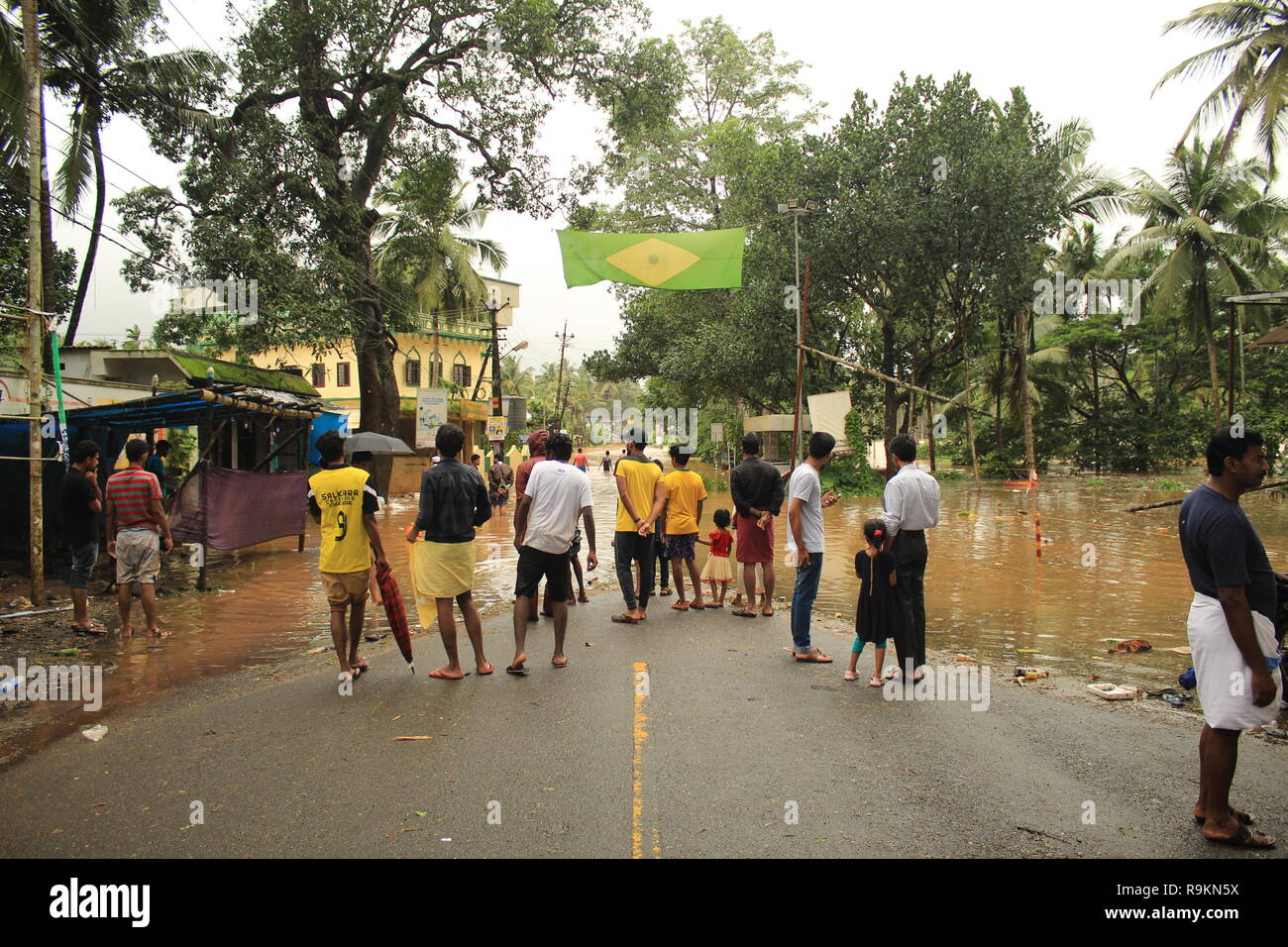 Leute um eine In-tank-Straße in Kerala nach schweren Überschwemmungen und Regen geschehen. Ein Brasilien Flag wird während der WM 2018 hing. Stockfoto
