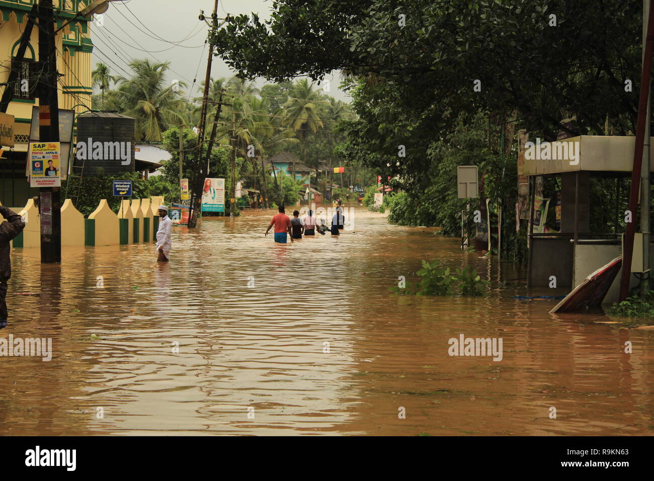 Menschen waten durch Wasser während Kerala Flut 2018 entlang einer überfluteten Straße. Schwere Überschwemmungen im Süden Indiens. Stockfoto