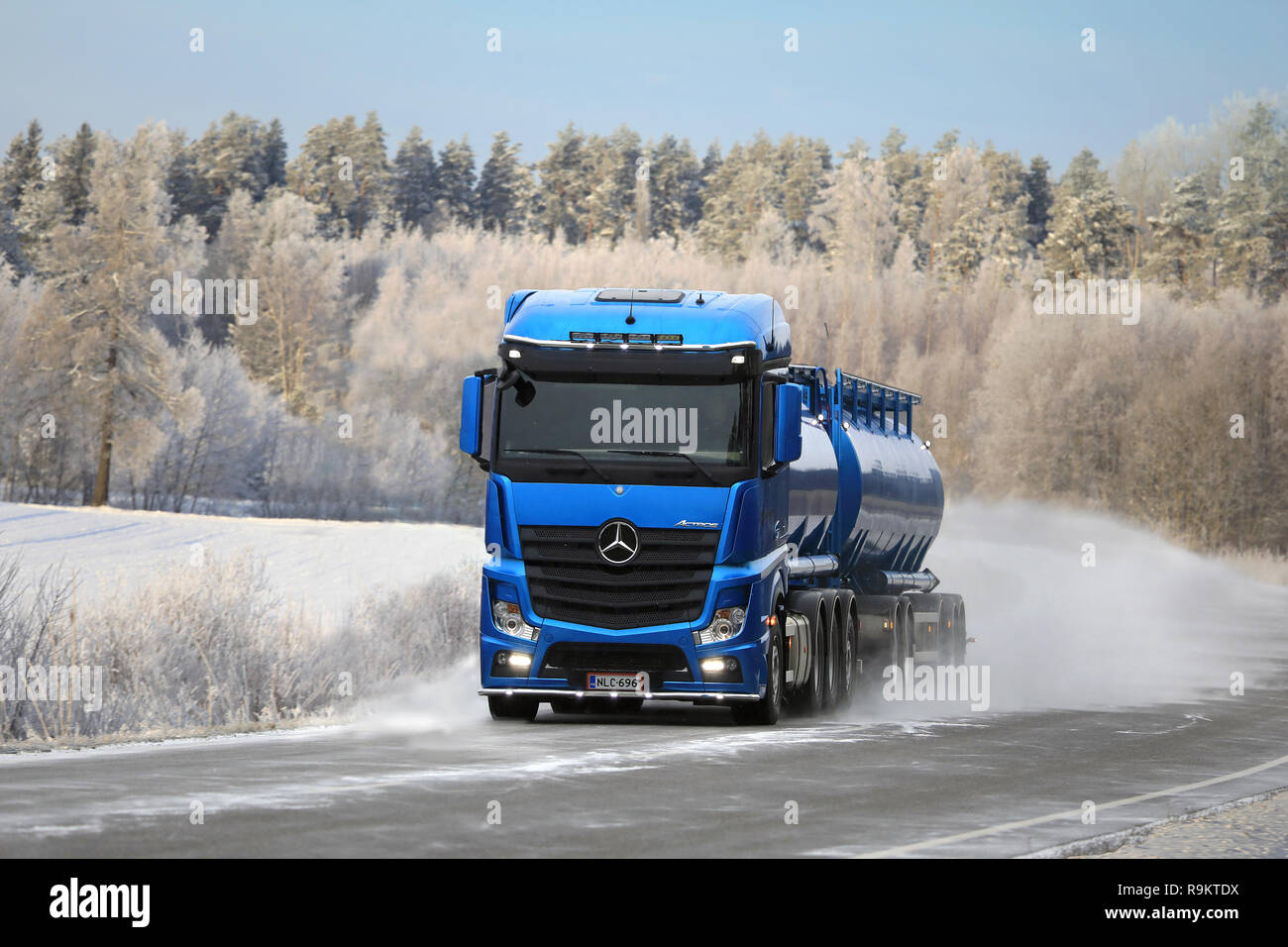 Blaue Mercedes-Benz Actros tank-Lkw der Kuljetusliike Markus Hanninen liefert Last auf verschneiten Autobahn durch die schöne Winterlandschaft in Salo, Finla Stockfoto