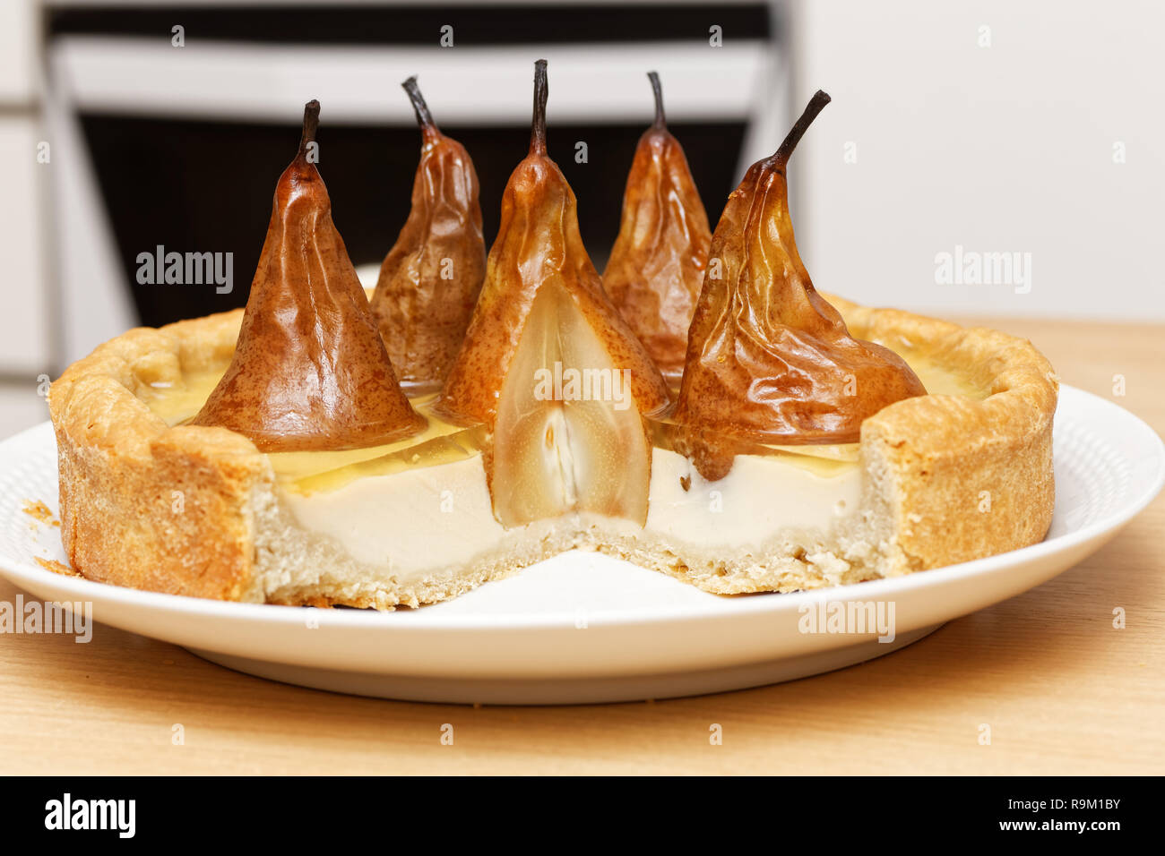 Pear-Kuchen mit Sahne Butter und Marmelade mit abgeschnitten Stücke auf hölzernen Tisch gegen verwackelte Küche Hintergrund Stockfoto