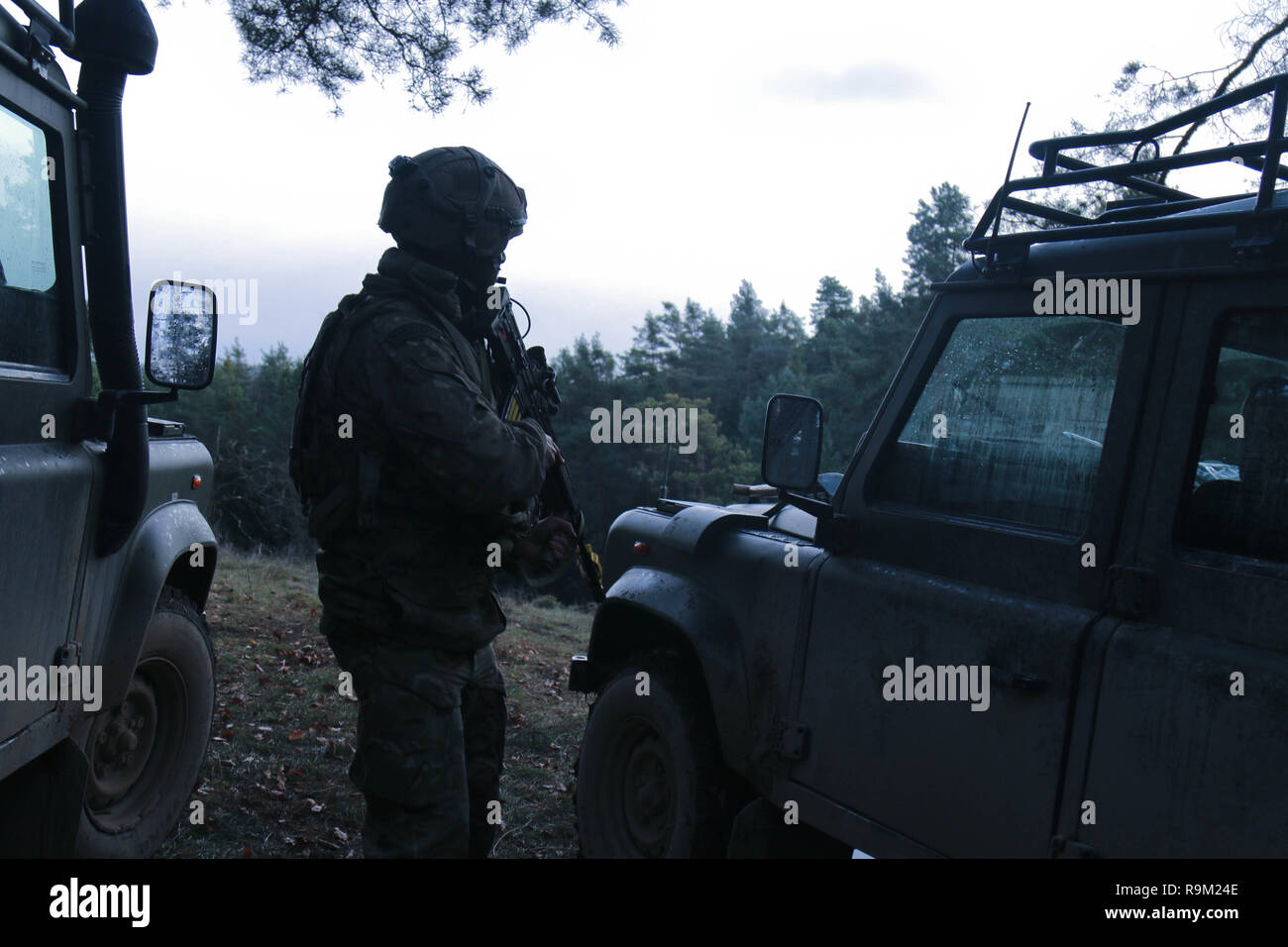 Ein britischer Soldat an 2nd Battalion, 5th Cavalry Regiment, 1st Armored Brigade Combat Team, 1.Kavallerie Division, wacht auf einem Hügel mit Blick auf die 2-5 taktische Cav's Operations Center während der kombinierten Lösung XI, Hohenfels, Deutschland, Dez. 8, 2018. Kombinierte Lösung XI am Joint Multinational Readiness Center ist die letzte Übung in 1-1 CD's Rotation zur Unterstützung der Atlantischen lösen in Europa, die die Interoperabilität der US-Streitkräfte mit ihren NATO-Verbündeten und Partnern evaluiert. (U.S. Army National Guard Foto von Sgt. Jamar Marcel Pugh, 382 Öffentliche Angelegenheiten Ablösung/1 ABC Stockfoto