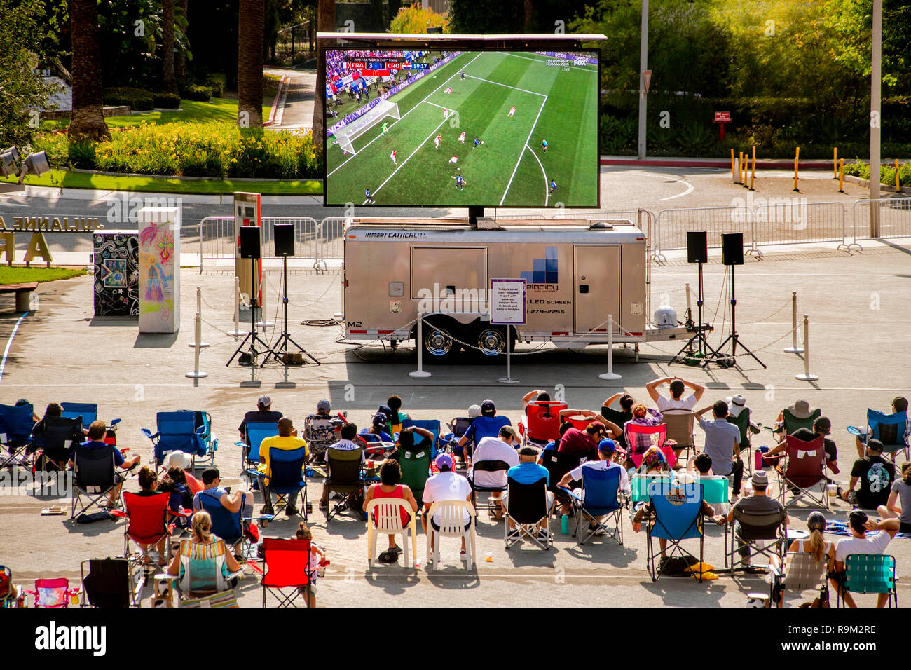 Tagsüber ein Publikum Uhren eine Fußball-WM Spiel auf einen gigantischen Outdoor TV-Bildschirm in Costa Mesa, CA. Stockfoto
