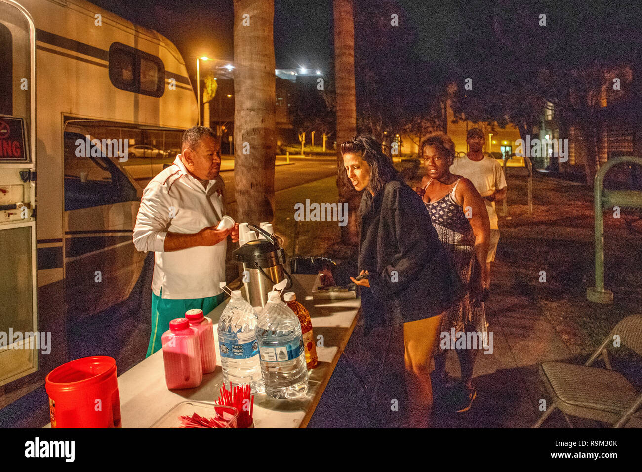 Außerhalb eines spezialisierten Van, kaukasischen und Spanischer freiwilliger gratis Essen multirassischen freigegeben County Gefängnis Insassen auf einer Straße in der Nacht in Santa Ana, CA. Stockfoto