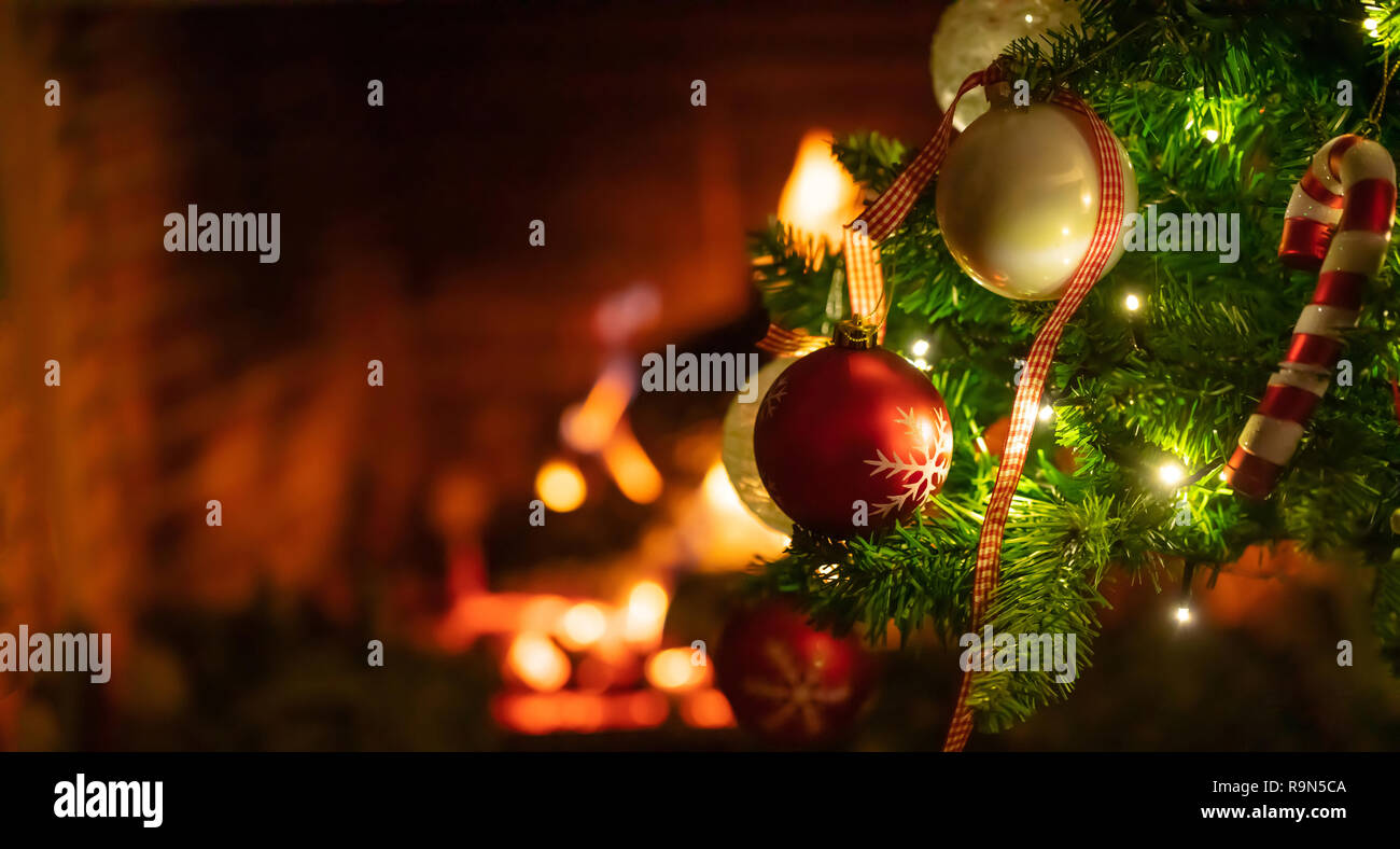 Weihnachten, warmes Zuhause. Weihnachtsbaum in der Nähe auf unscharfen brennenden Kamin Hintergrund Kopie Raum Stockfoto
