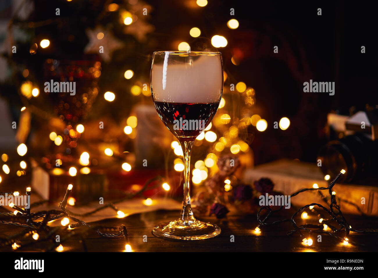 Festliche Atmosphäre in den mit einem Glas Rotwein. Rauch kriechen in Clubs in Glas und Licht bokeh Hintergrund. Weihnachten, Silvester oder Sa Stockfotografie - Alamy