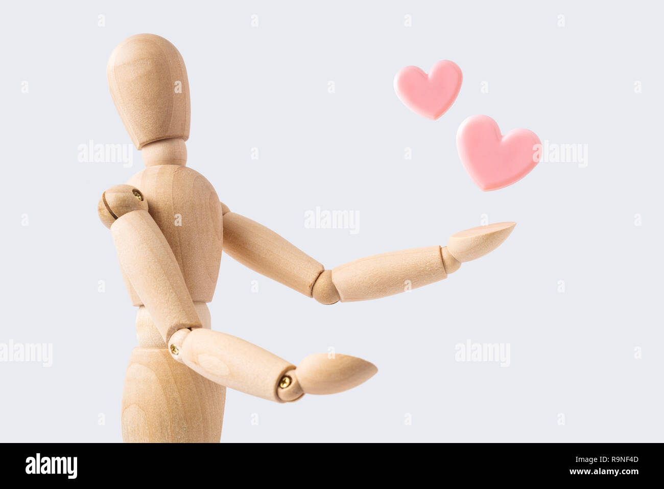 Business- und Designkonzept - hölzerne Puppe mit rosa Herz auf weißem Hintergrund. Das Symbol des Glücks Stockfoto