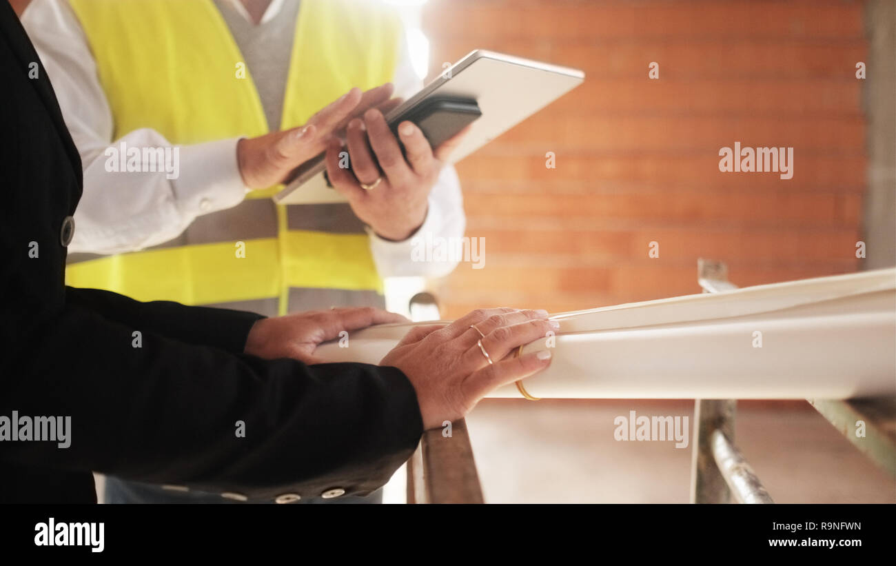 Frauen und Männer treffen im Bau. Teamwork mit Meister sprechen mit dem Ingenieur holding Blaupausen. Fokus auf Hochzeit Ring an der Hand des Weiblichen. C Stockfoto