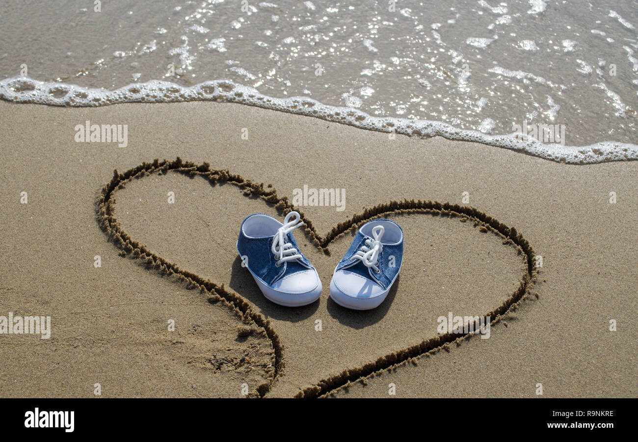 Baby Schuhe am Strand in Herzform Stockfoto