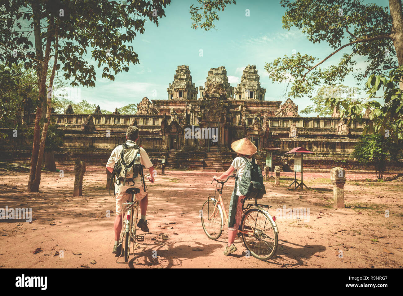 Touristische paar Radfahren rund um Tempel Angkor, Kambodscha. Ta Keo Gebäude Ruinen im Dschungel. Umweltfreundliche Tourismus Reisen, getönten Bild. Stockfoto