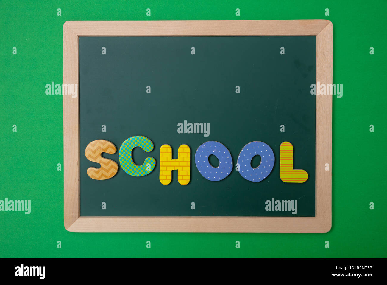 Schule Konzept. Grüne Tafel mit Holzrahmen, Word, text Schule in bunte Buchstaben, grüne Wand Hintergrund, kopieren Raum Stockfoto