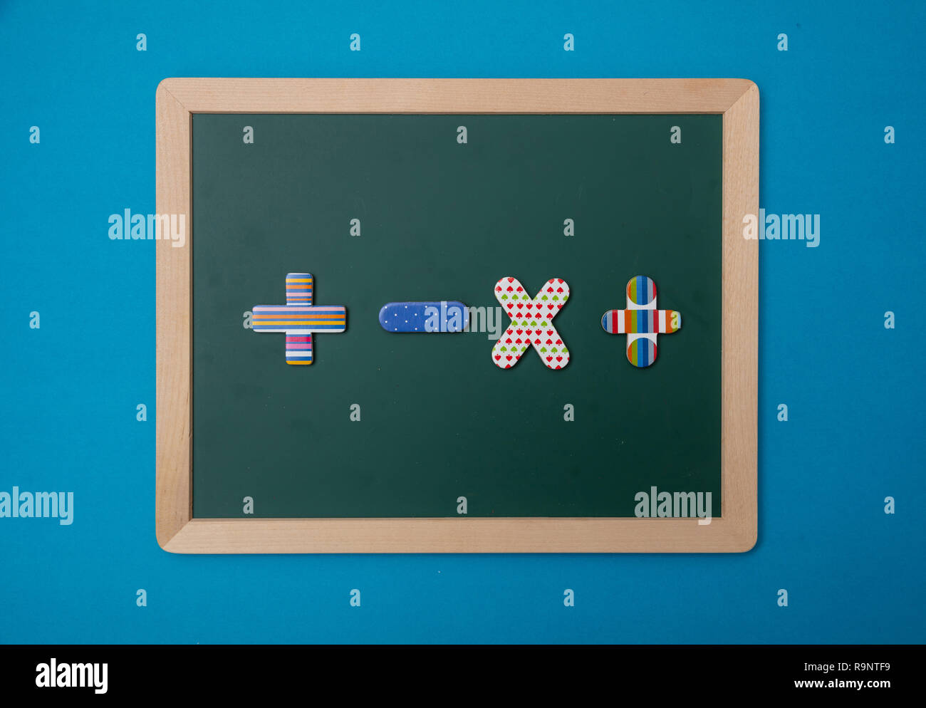 Mathematik, Schule Konzept. Grüne Tafel mit Holzrahmen, bunte Betrieb Zeichen, blauer Hintergrund Stockfoto