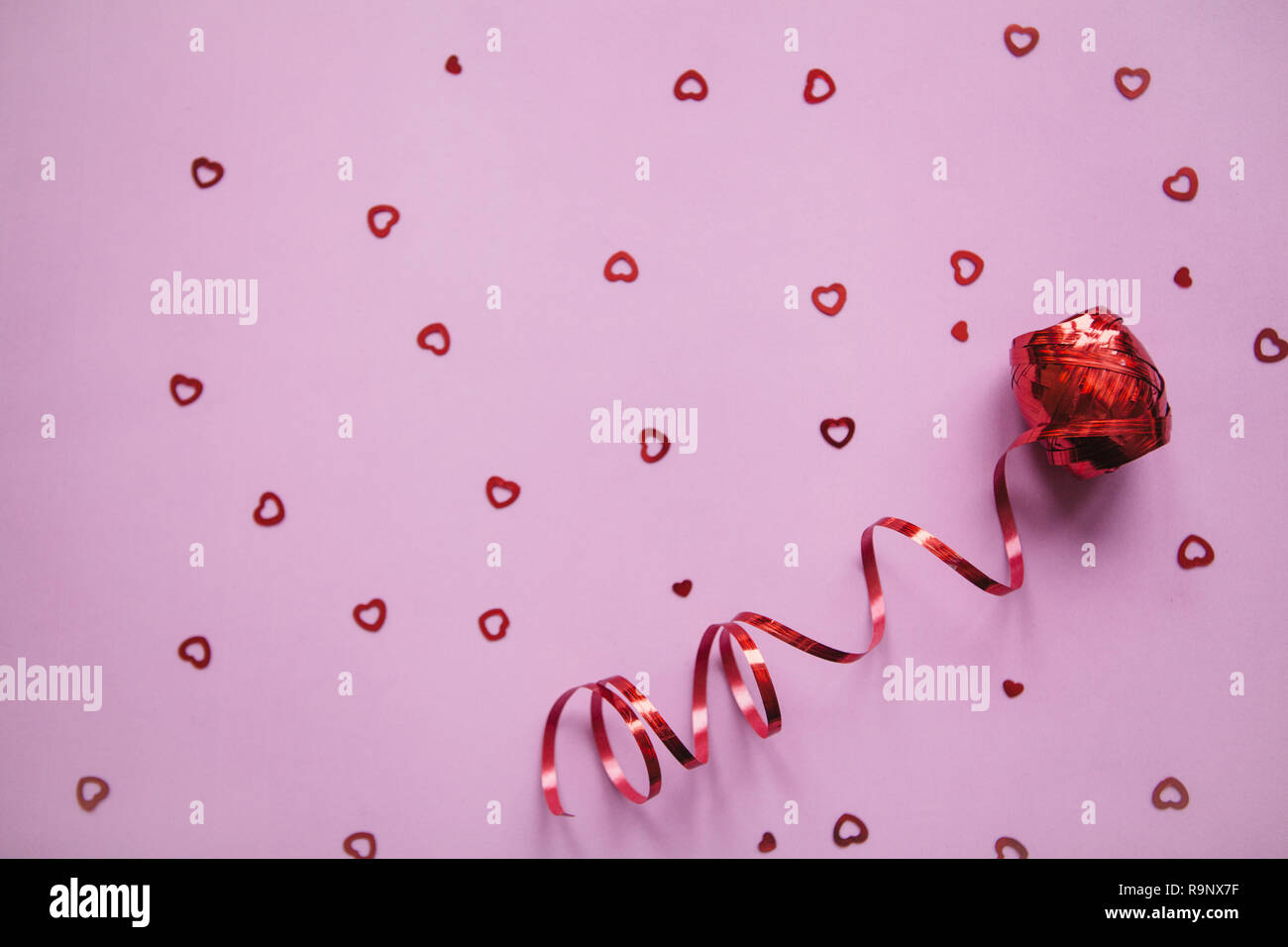 Red Ribbon und viele kleine Herzen. Valentine's Day Feier Konzept im minimalistischen Stil. Urlaub Elemente. Stockfoto