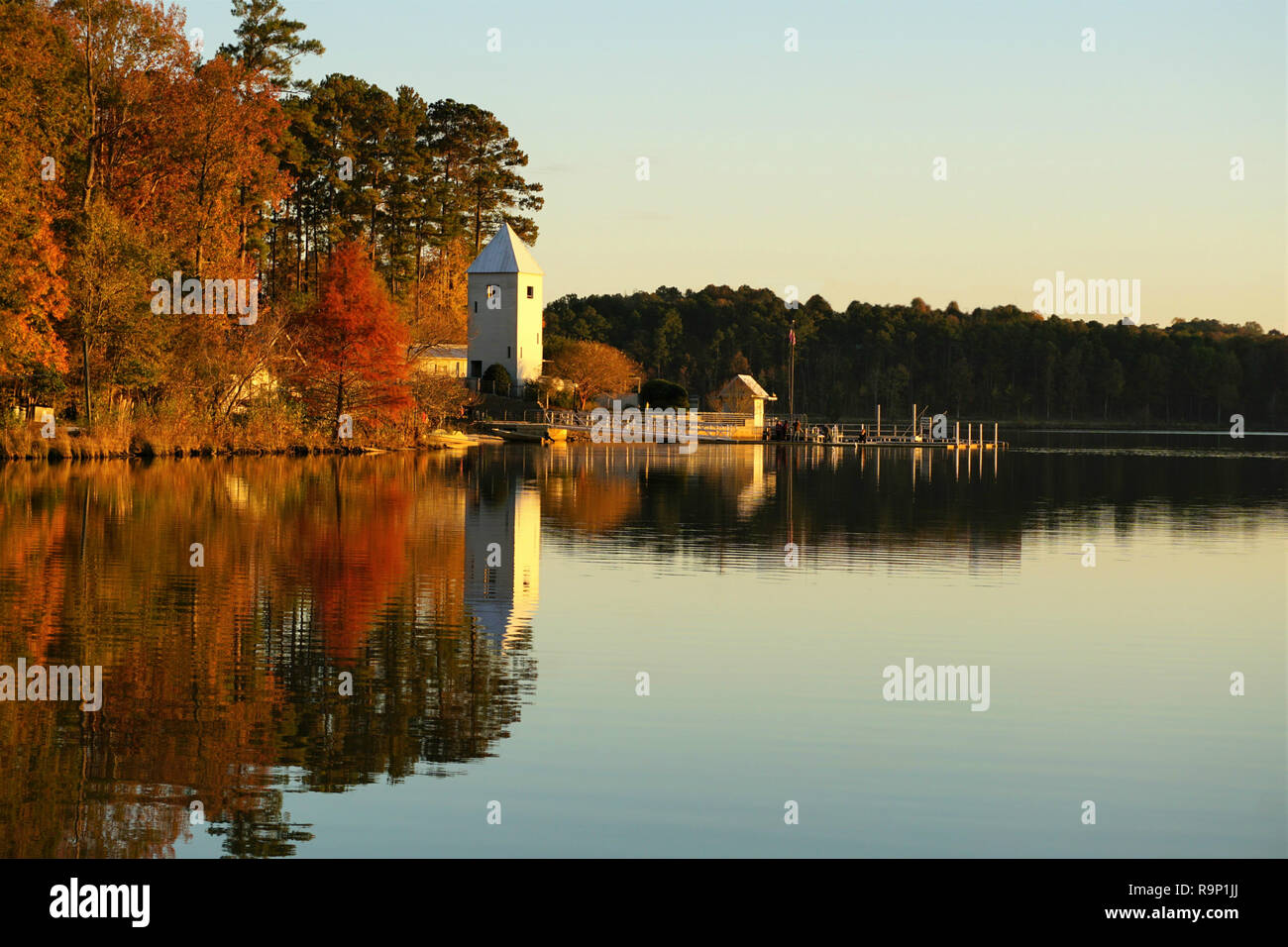 Reflexion von Bootshaus und Falllaub in einem ruhigen See Stockfoto