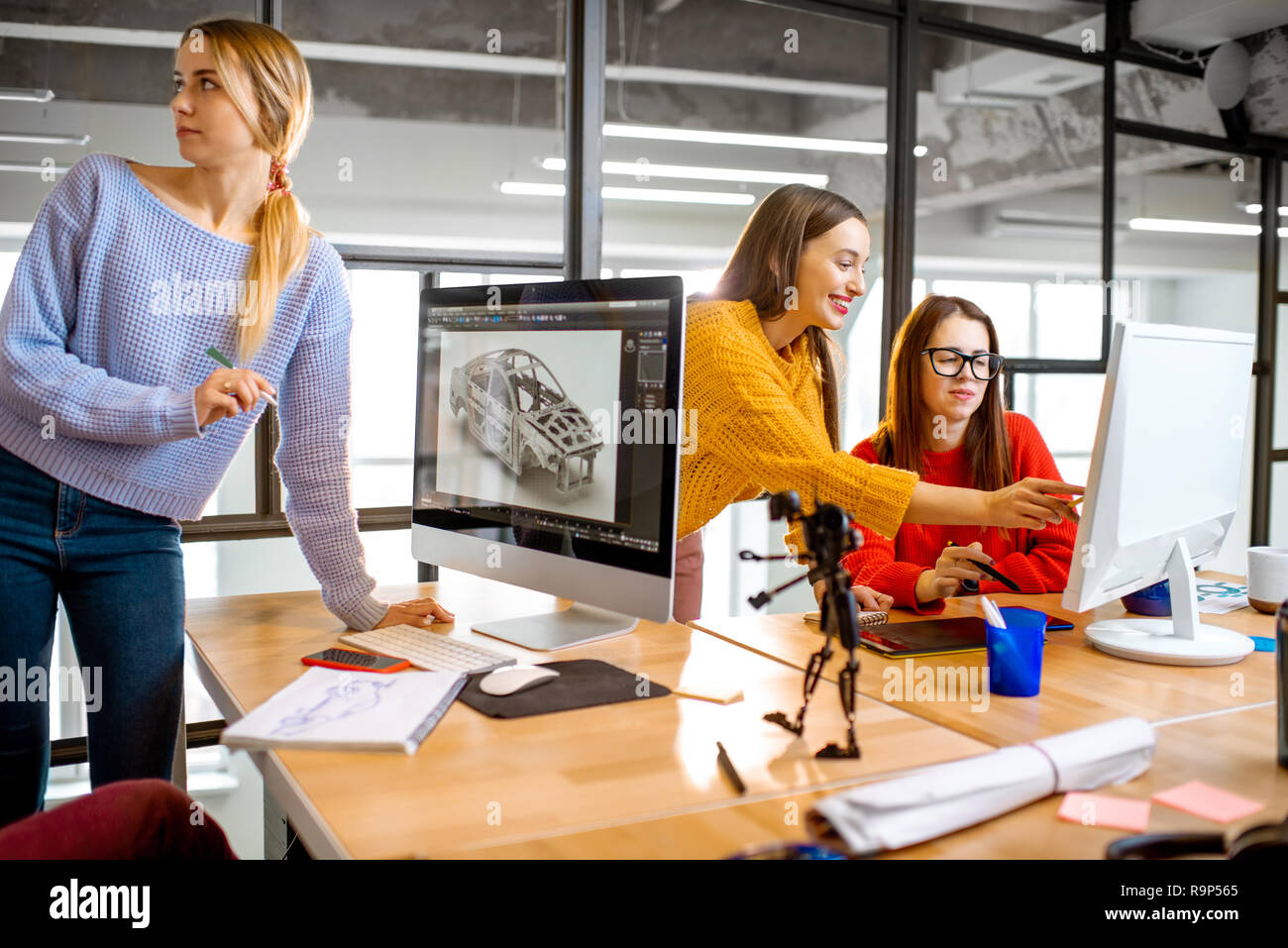 Gruppe von jungen, kreativen Mitarbeitern Entwerfen eines Pkw-Modell am Arbeitsplatz mit Computern im modernen Büro innen Stockfoto