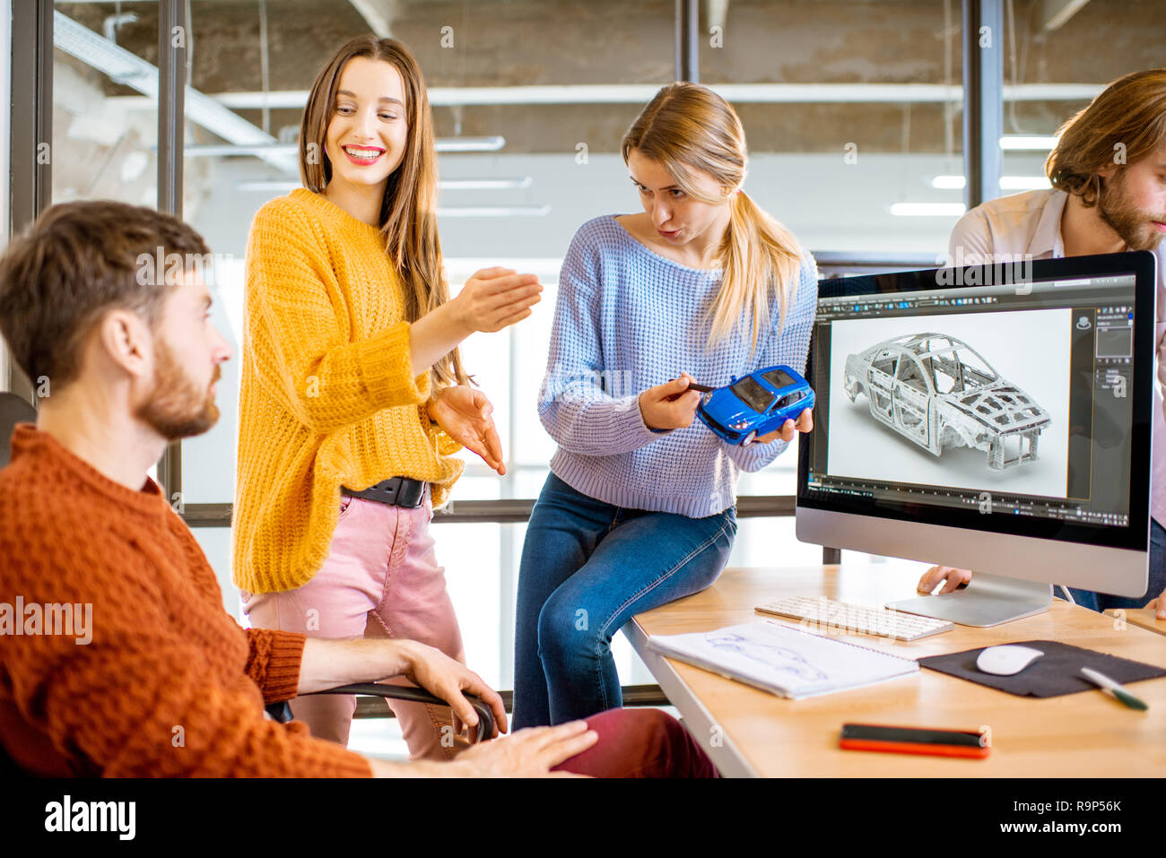 Gruppe von jungen, kreativen Mitarbeitern Entwerfen eines Pkw-Modell am Arbeitsplatz mit Computern im modernen Büro innen Stockfoto