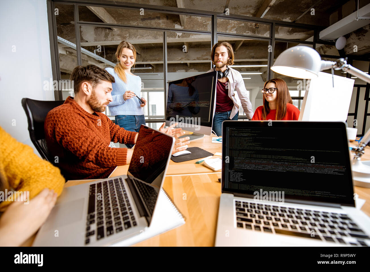 Gruppe von jungen Mitarbeiter gekleidet beiläufig zusammen auf dem Computer in das moderne Büro innen Stockfoto