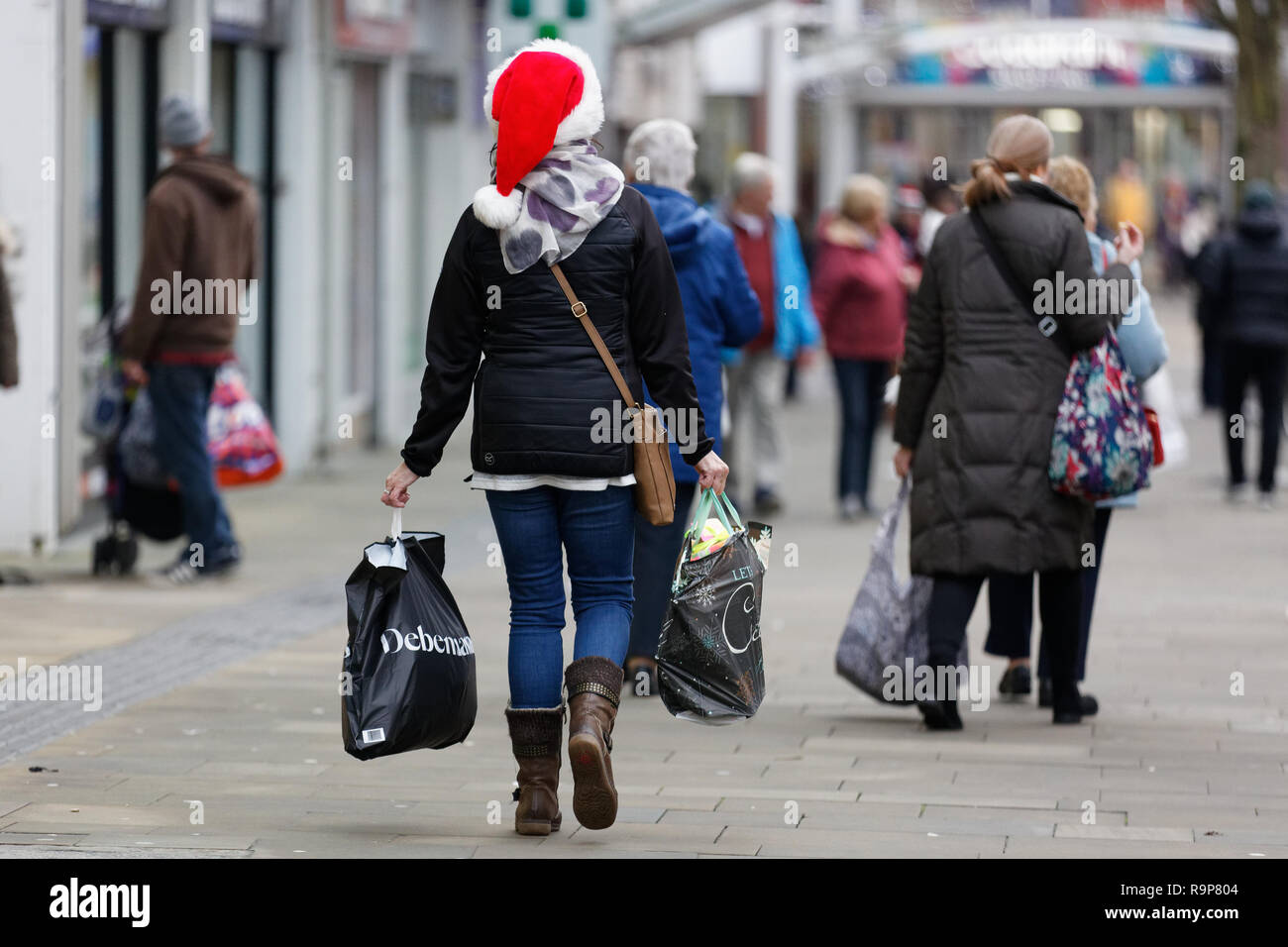 Last Minute Weihnachten Shopper mit einer Santa Hut in der Oxford Street, Swansea, Wales, UK. Montag, 24 Dezember 2018 Stockfoto