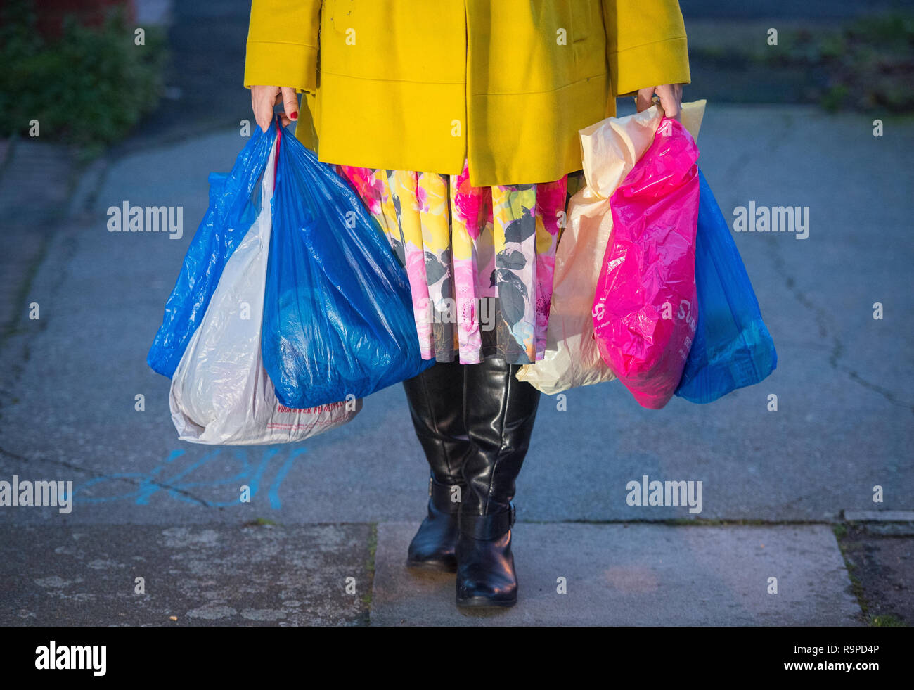 Eine Frau trägt Einkaufen in Plastiktüten in London. Käufer werden 10 p für eine Tragetasche in allen Stores in England unter den Plänen, die durch das Klima Sekretärin bezahlen. Stockfoto