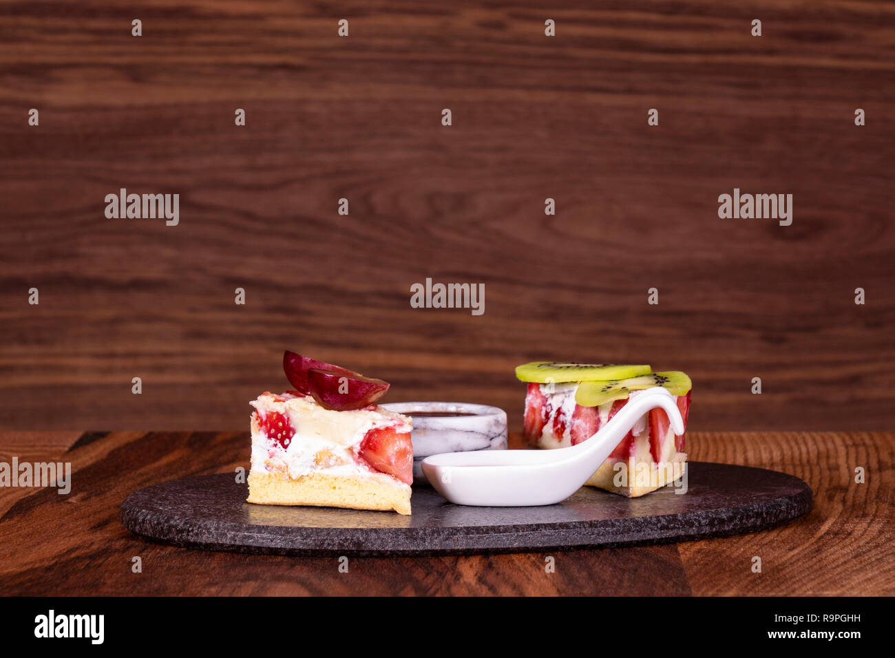 Stück Kuchen auf schwarze Platte mit Erdbeeren. Holz- Hintergrund Stockfoto