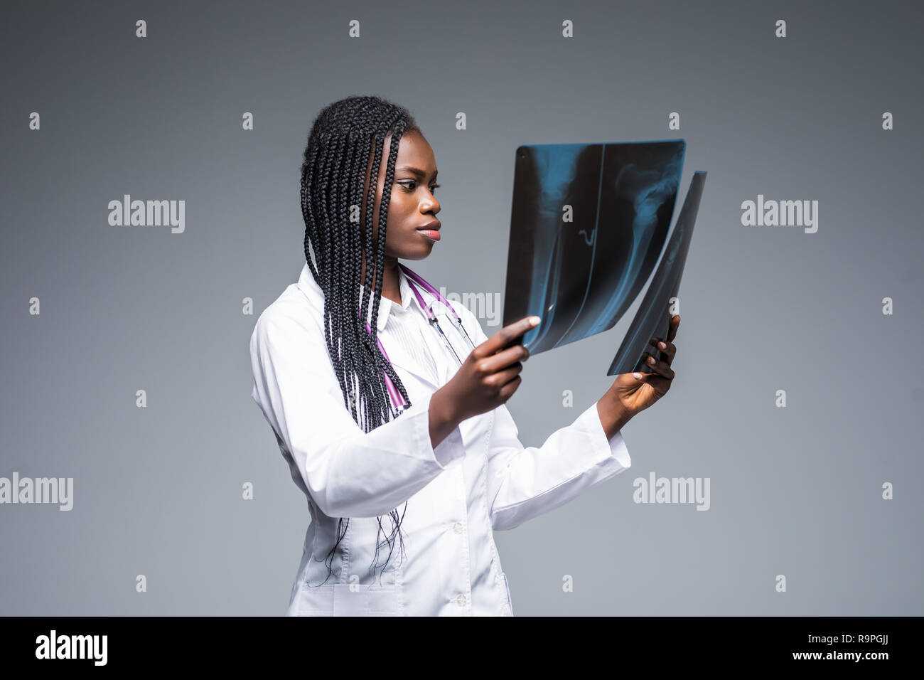 Junge afrikanische Ärztin bei einem x-ray auf grauem Hintergrund Stockfoto