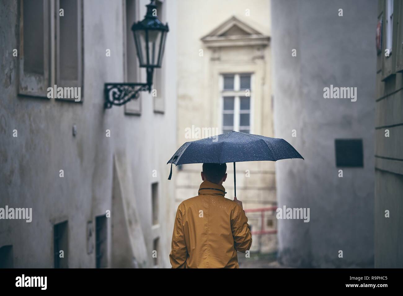Mann mit Schirm wandern im Regen. Alte Stadt Straße in Prag, Tschechische Republik Stockfoto
