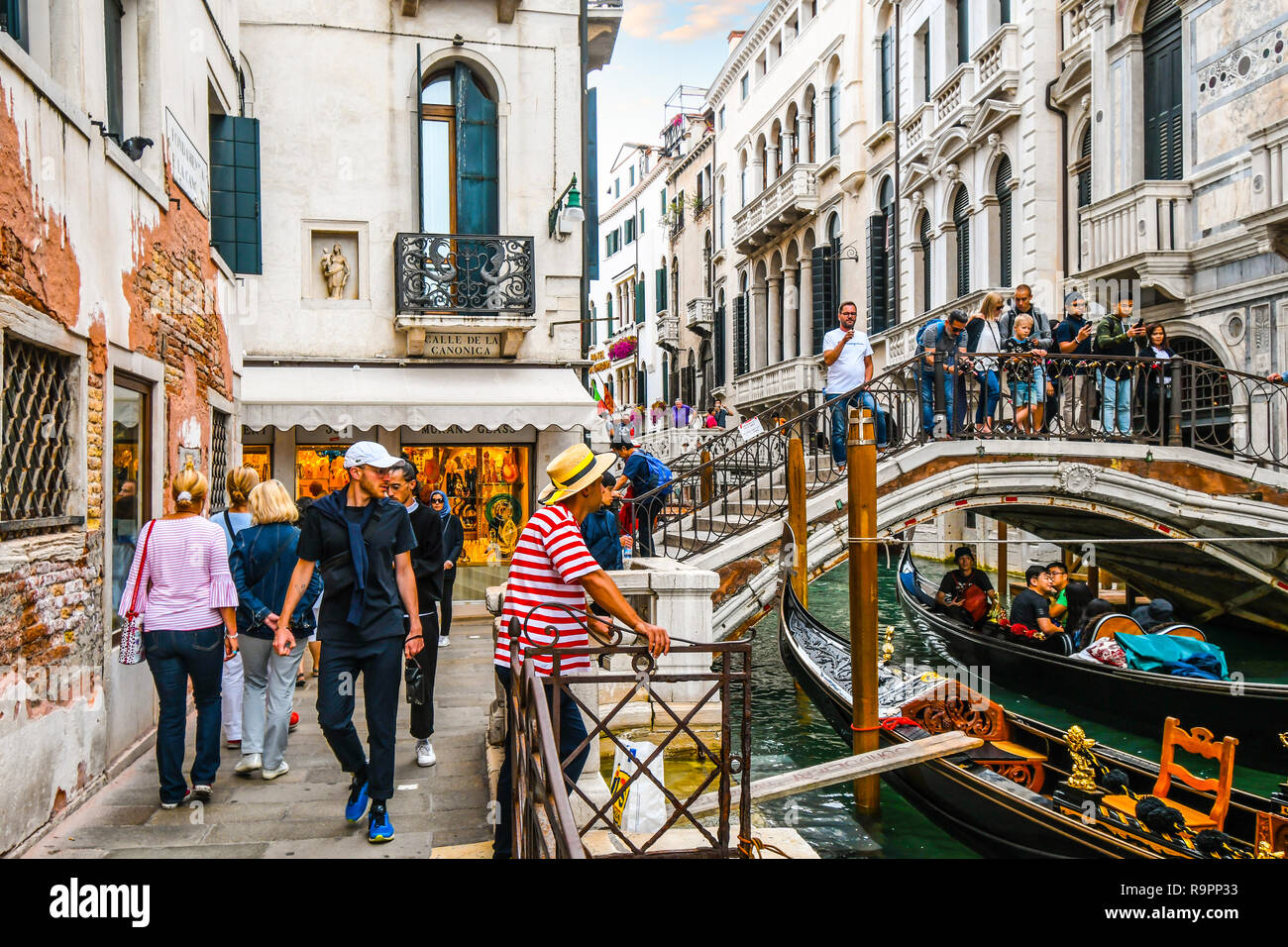 Einem langen Kanal an der Calle de La Canonica als Touristen, überqueren Sie die Brücke über die Gondeln mit Touristen und ein gondoliere wartet auf Kunden in Venedig Italien Stockfoto