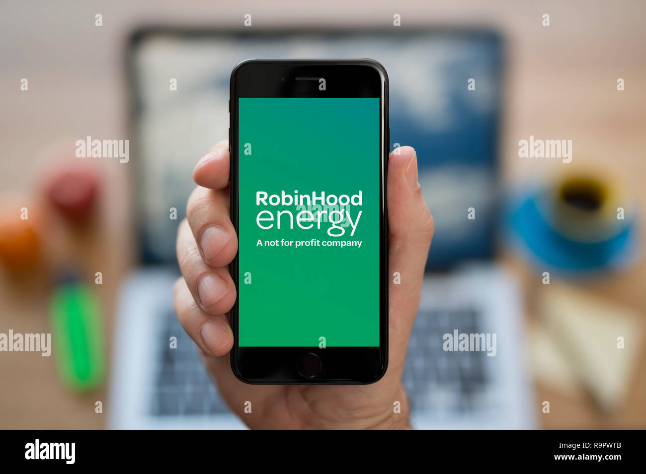Ein Mann schaut auf seinem iPhone die zeigt die Robin Hood Energie Logo (nur redaktionelle Nutzung). Stockfoto