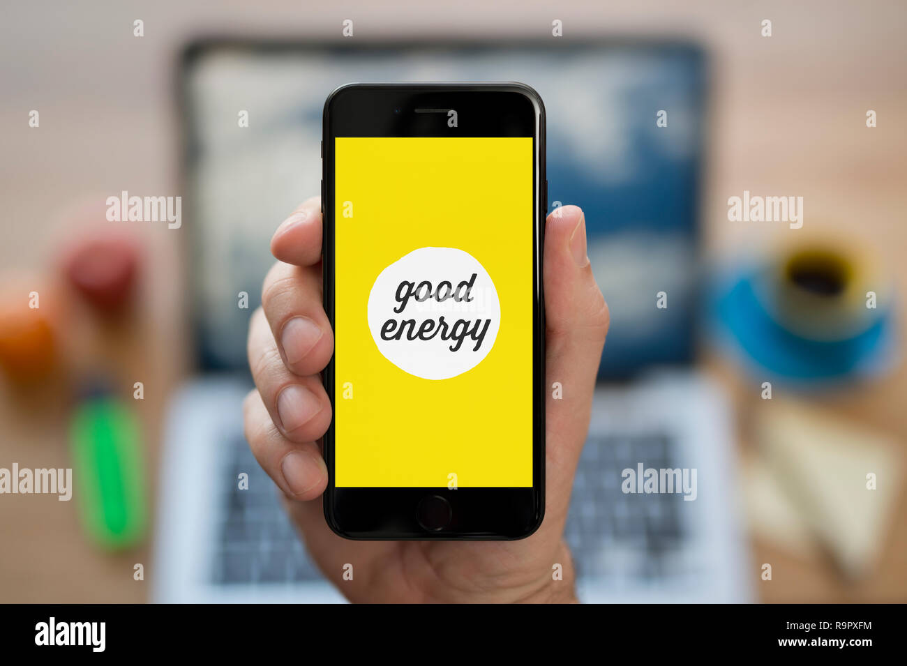 Ein Mann schaut auf seinem iPhone, das zeigt die gute Energie Logo (nur redaktionelle Nutzung). Stockfoto