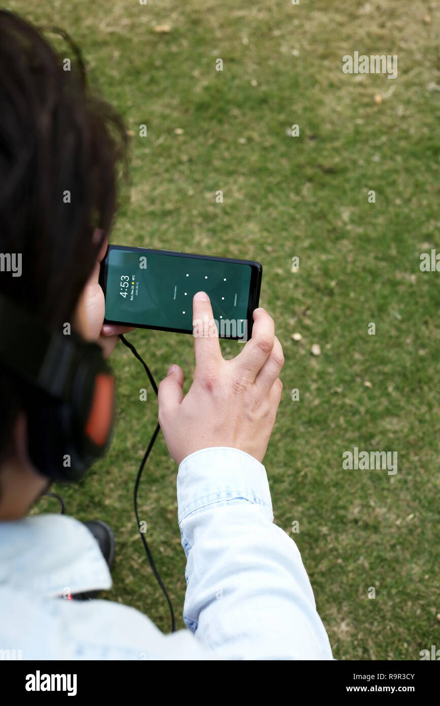 Junge ist das Hören von Musik mit Kopfhörer und Sie ihr Smartphone. Stockfoto